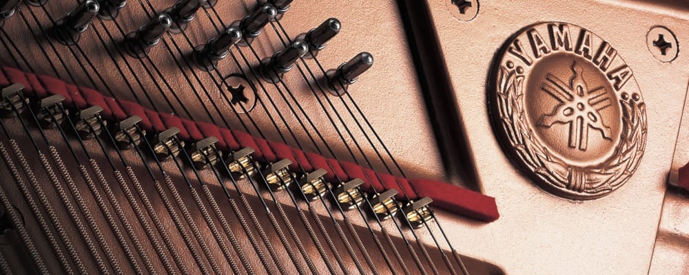 Closeup of soundboard and ribs with Yamaha logo (three intersecting tuning forks).