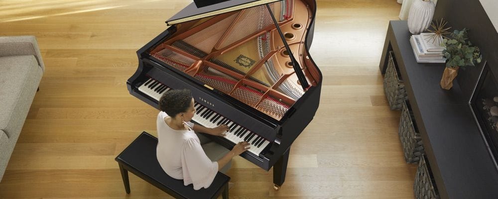 View from above as a woman plays a Yamaha grand piano in her living room.