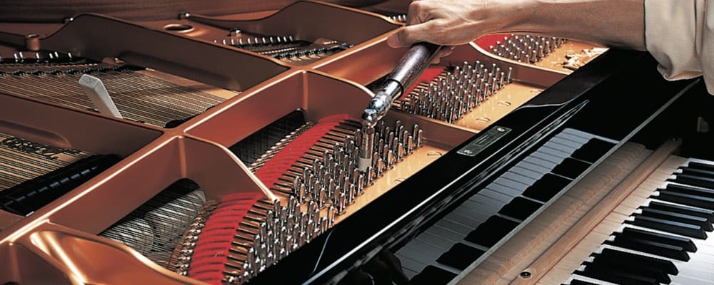 Someone is using a rachet tool to turn the pins that tighten or loosen the piano string in a grand piano.